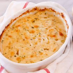 a casserole dish with cheese and herbs in it on a red and white towel