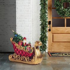 a gold sleigh with christmas decorations on the floor and wreaths around it