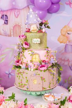 a three tiered cake is decorated with flowers and fairy houses on it's sides