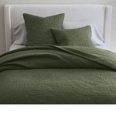 a bed with green bedspread and pillows