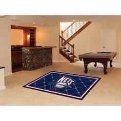 a living room with a pool table and foosball in the center, stairs leading up to an upper floor