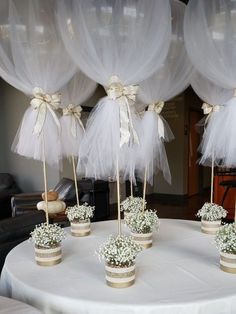 there are many small vases with flowers in them on the table and some white tulle