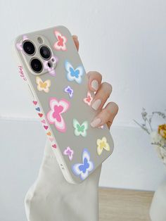 a woman holding up her phone case with butterflies on it