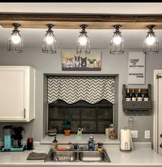 a kitchen with several lights hanging over the stove top and sink area, along with wine bottles on the counter