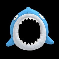 a stuffed shark with its mouth open and it's teeth wide open on a black background