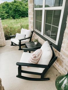 two rocking chairs sitting on the front porch with pillows and flowers in vases next to them