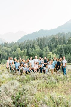 a group of people posing for a photo in front of some trees and hills with mountains in the background