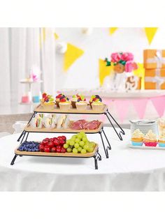 three tiered trays with cupcakes and fruit on them sitting on a table