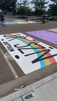 people riding skateboards on the side of a street painted with different colors and shapes