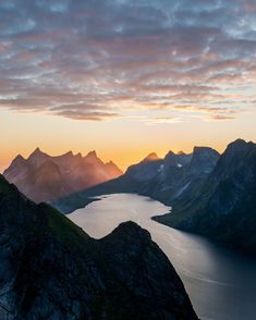 the sun is setting over some mountains and water