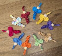 small crocheted toys are arranged in a circle on a wooden surface with buttons