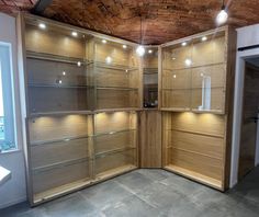 an empty room with wooden shelves and lights on the ceiling is lit by recessed lighting