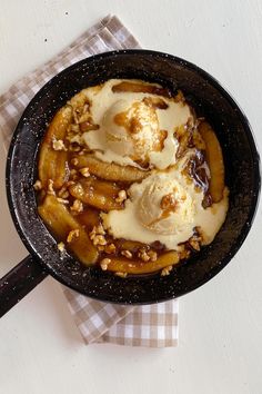 a skillet filled with ice cream and bananas on top of a checkered napkin