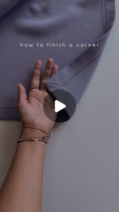 a woman's hand holding onto the side of a gray t - shirt that says, how to finish a corner