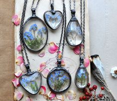 several necklaces with flowers and birds in them on a piece of paper next to other items