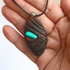 Embrace the serene beauty of nature and the calming influence of healing stones with this exquisite  Ebony Necklace with Green Howlite stone.  This unique piece showcases the rustic charm of a leaf-shaped grain pattern, thoughtfully inlaid with the vibrant tranquility of green howlite mineral. Not only is howlite known for its soothing properties that calm an overactive mind and promote restful sleep, but it is also revered for connecting its wearer to a higher spiritual consciousness, encouragi Bohemian Raw Stone Pendant Necklace, Nature-inspired Raw Stone Healing Jewelry, Nature-inspired Raw Stone Jewelry For Healing, Bohemian Pendant Necklace With Raw Stone, Nature-inspired Pendant Necklace With Large Stone, Natural Carved Nature-inspired Necklace, Nature-inspired Carved Natural Necklace, Adjustable Carved Nature-inspired Necklaces, Nature-inspired Oval Pendant Jewelry For Healing