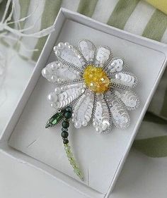 a white box with a flower brooch in it