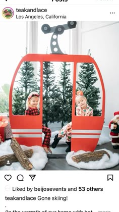 two children sitting in a ski lift with christmas decorations on the floor and trees behind them