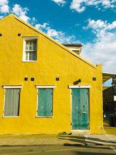 a yellow building with green doors and windows