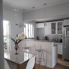 a kitchen with white cabinets and counter tops next to a dining room table in front of an open door