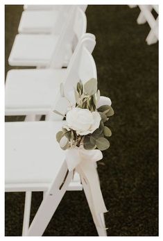 rows of white folding chairs with flowers and greenery tied to the back of them