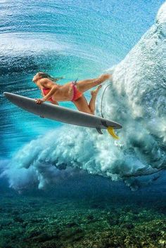 a woman riding a surfboard on top of a wave in the ocean under water