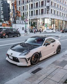 a white sports car is parked on the side of the road in front of some buildings