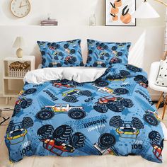 a blue bed with monster trucks on it in a bedroom next to a white wall