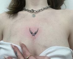 a close up of a person with a tattoo on their chest holding a chain around her neck