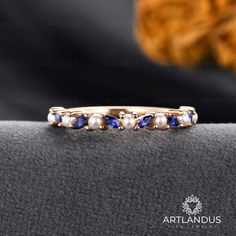 a gold ring with blue and white stones on it, sitting on a black cloth