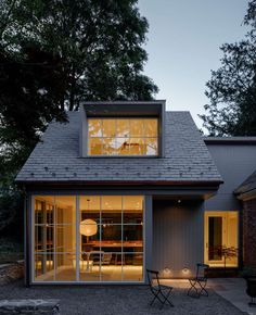 a small house with large windows and lights on the front door is lit up at night