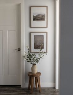 there is a vase with some flowers on the table in front of the door and pictures on the wall