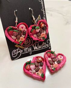 three pink heart shaped earrings with chocolates in the shape of hearts and flowers on them