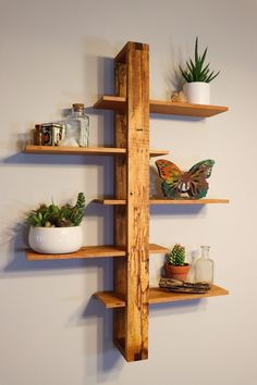 three wooden shelves with plants and other items on them in the corner of a room