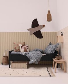 a room with a bed, table and stuffed animals hanging from the wall next to it