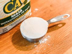 a wooden table with a measuring spoon and can of cat