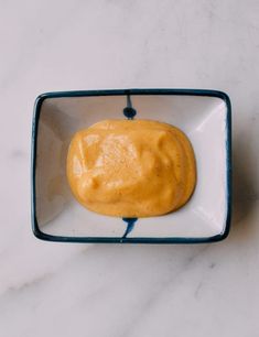 a square white bowl filled with food on top of a table