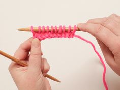 two hands holding knitting needles and crochet hook