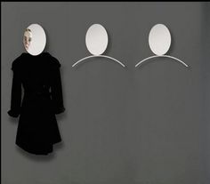 a woman standing in front of three white circles on a wall with her head turned to the side