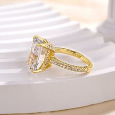 a yellow gold ring with an oval cut diamond and pave set diamonds on the sides