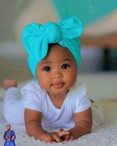 a baby wearing a blue headband laying on top of a bed