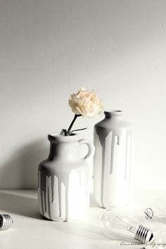 two white vases sitting on top of a table next to an electric toothbrush