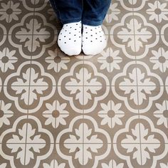 a person standing on a tiled floor with their feet propped up against the tile in front of them