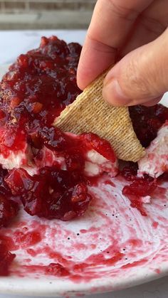 someone is dipping some kind of food into a white bowl with cranberry sauce