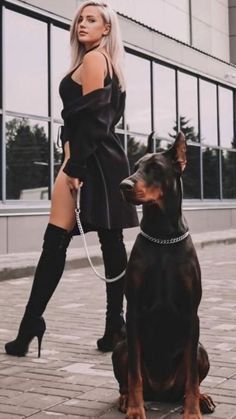 a woman standing next to a black and brown dog wearing thigh high boots with her legs crossed