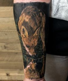 a man with a tattoo on his arm that has an image of a fox and cub