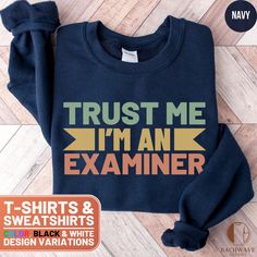 Show off your profession with this "Trust Me I'm an Examiner" design. Perfect for examiners to wear casually or for work. Makes a great gift for proud examiners or those who are studying to become one. Ideal for birthdays, holidays, or just because. Comfortable and stylish, it's a must-have for any examiner enthusiast! ❤️ HOW TO ORDER ❤️   1. Check out all the photos for sizing and color options.📏 2. Choose your perfect size and color from the drop-down menus!✨  3. Click "ADD TO CART" and feel free to add as many as you wish! 🛒  4. Hit "PROCEED TO CHECKOUT" and get ready to enjoy your awesome purchase! We will process your order and it will be ready for shipment in 1-5 days!🚀 5. Want this design on another product or want to make slight alterations? Check the bottom of the description.✨ Fun Shirt, Your Awesome, Sweater Gift, Branded Sweatshirts, Black And White Design, Laid Back Style, Cozy Fashion, Trust Me, Neck Shirt