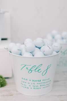 a bucket full of white golf balls sitting on top of a table