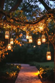 Hanging mason jar candles and string lights illuminating a rustic outdoor wedding aisle, creating a warm and intimate atmosphere for a fall garden ceremony. Bonfire Proposal, Luxury Cafe, Big Lantern, Night Picnic, Romantic Backyard, Outdoors Ideas, Fiction Story, Circle Mehndi