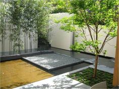 an outdoor courtyard with bamboo trees and water feature in the center, surrounded by white walls